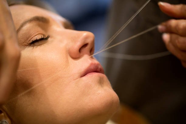 Épilation du visage au fil par une esthéticienne professionnelle en institut