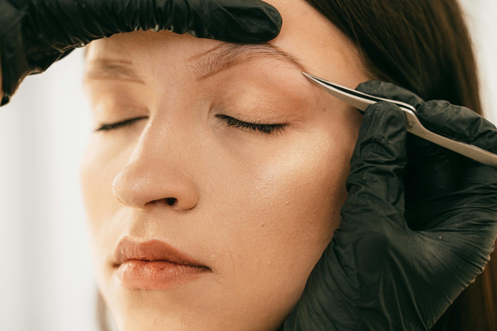 woman getting eyebrows plucked with tweezers