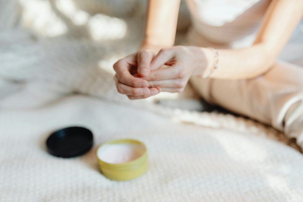 Close-up of a woman applying hand cream in a softly lit indoor setting, emphasizing skincare.